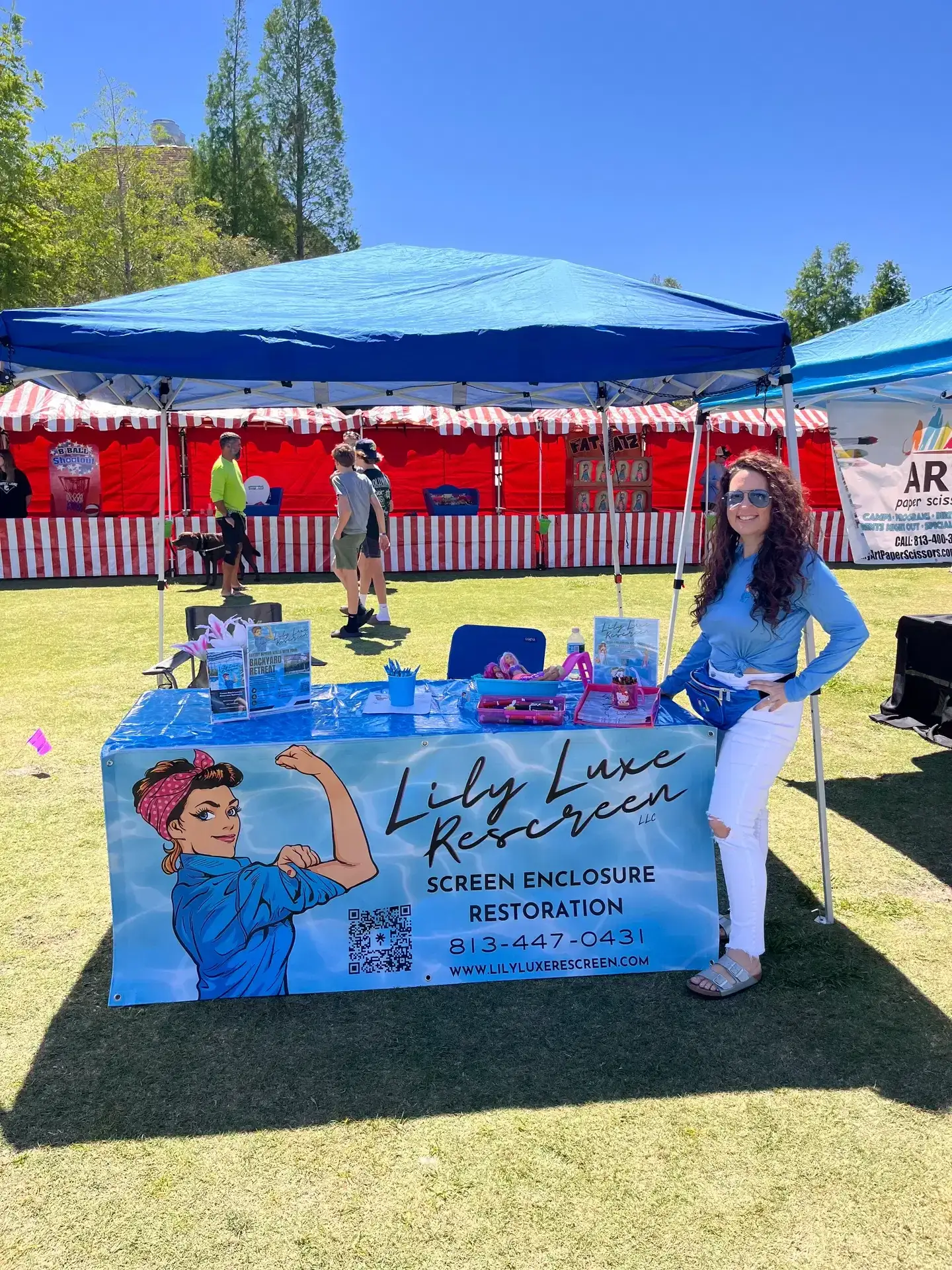 Amy at a community market beside a Lily Luxe Rescreen booth.