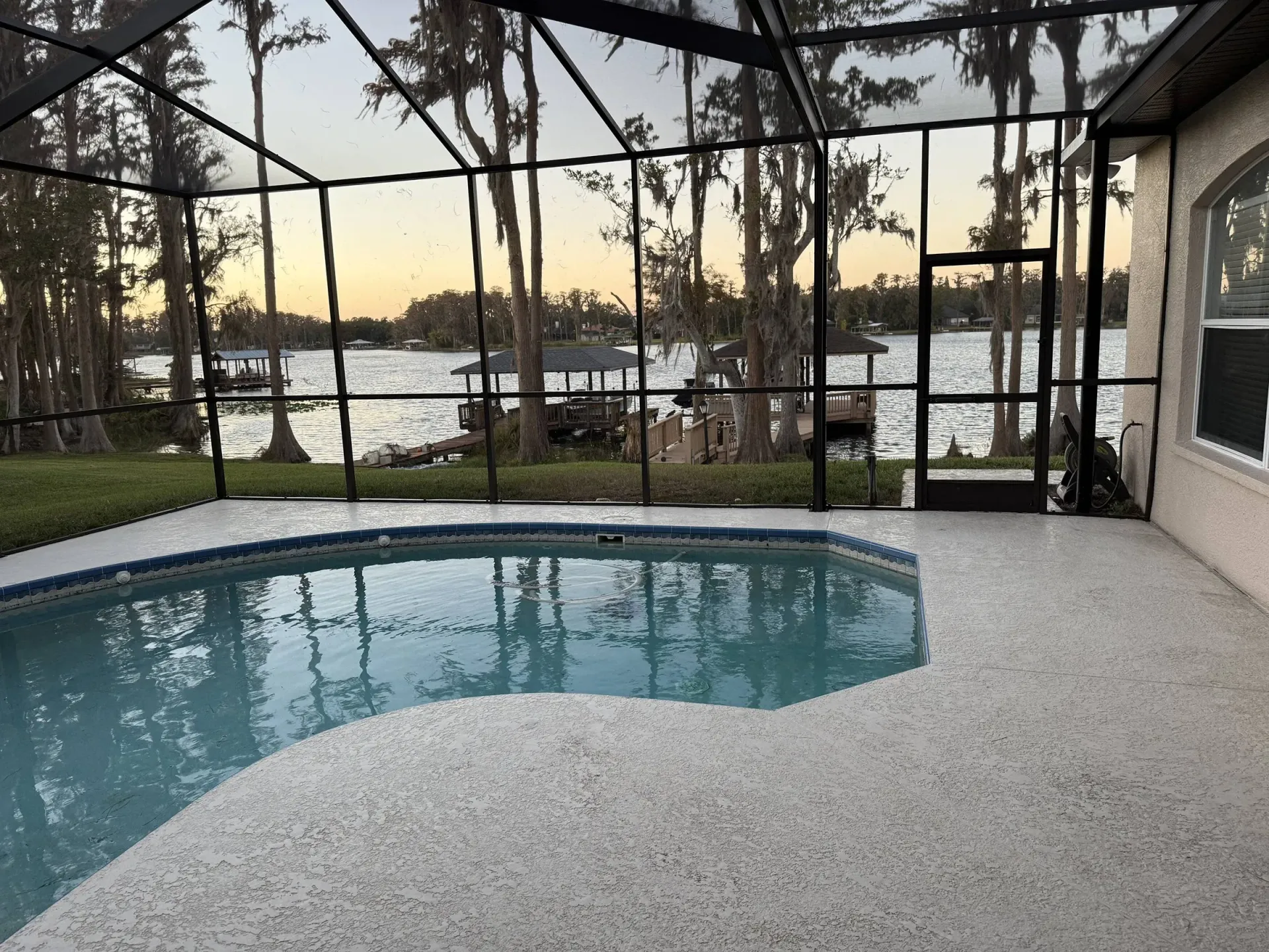 Freshly rescreened lakeside pool enclosure with clear panels and a luxury finish
