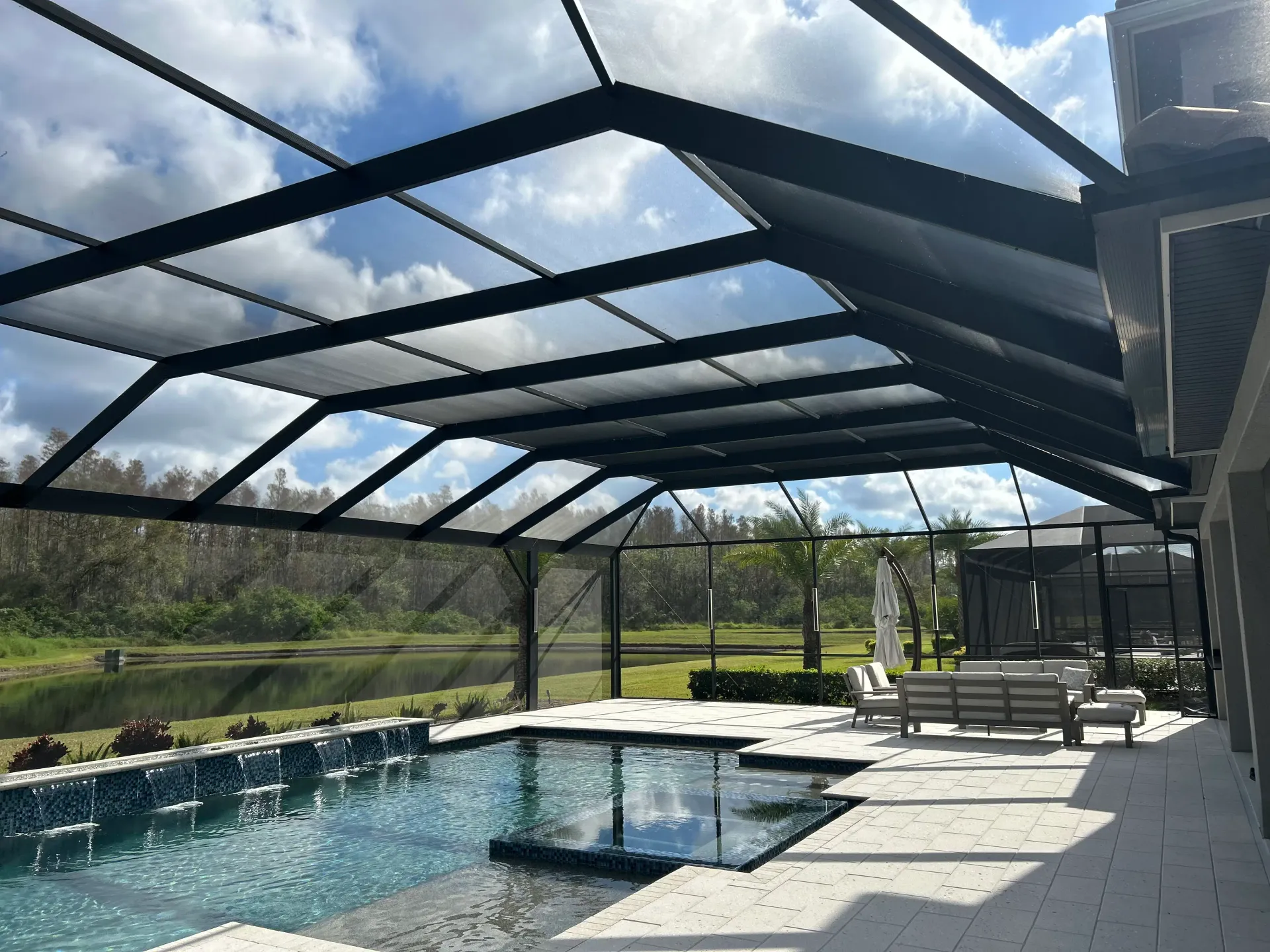 A freshly rescreened pool enclosure with clear views across the pool and surrounding landscape