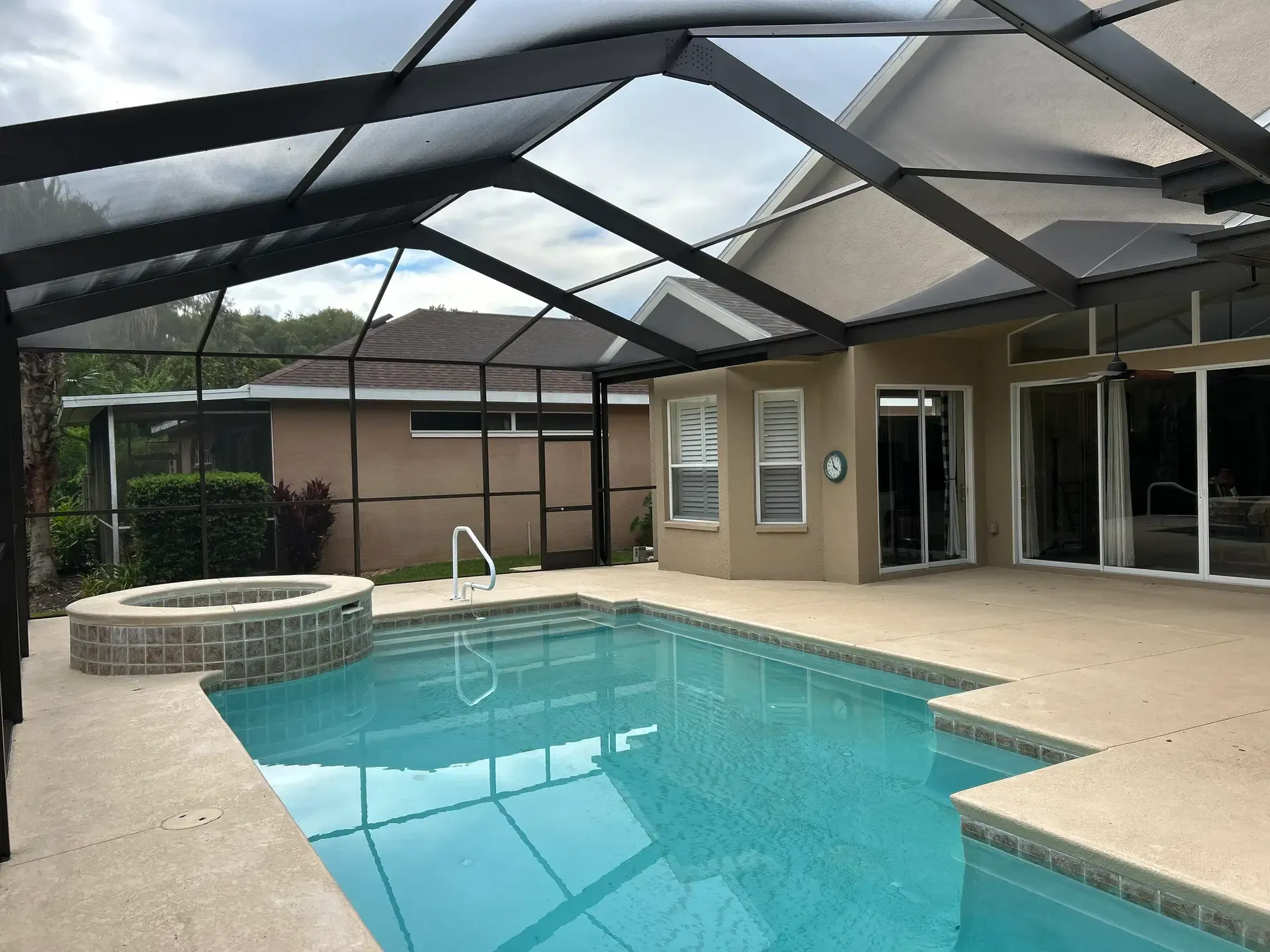 A cleanly rescreened black-frame pool enclosure with a clear view of the pool and spa