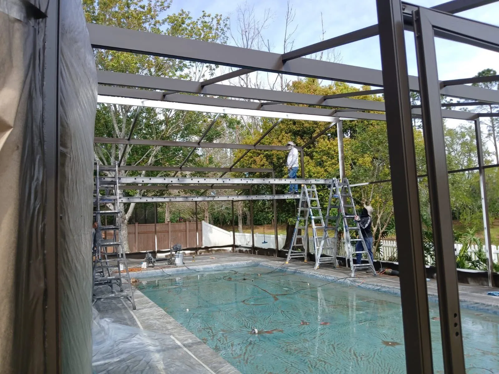 Professional crew working on a large pool enclosure rescreening project