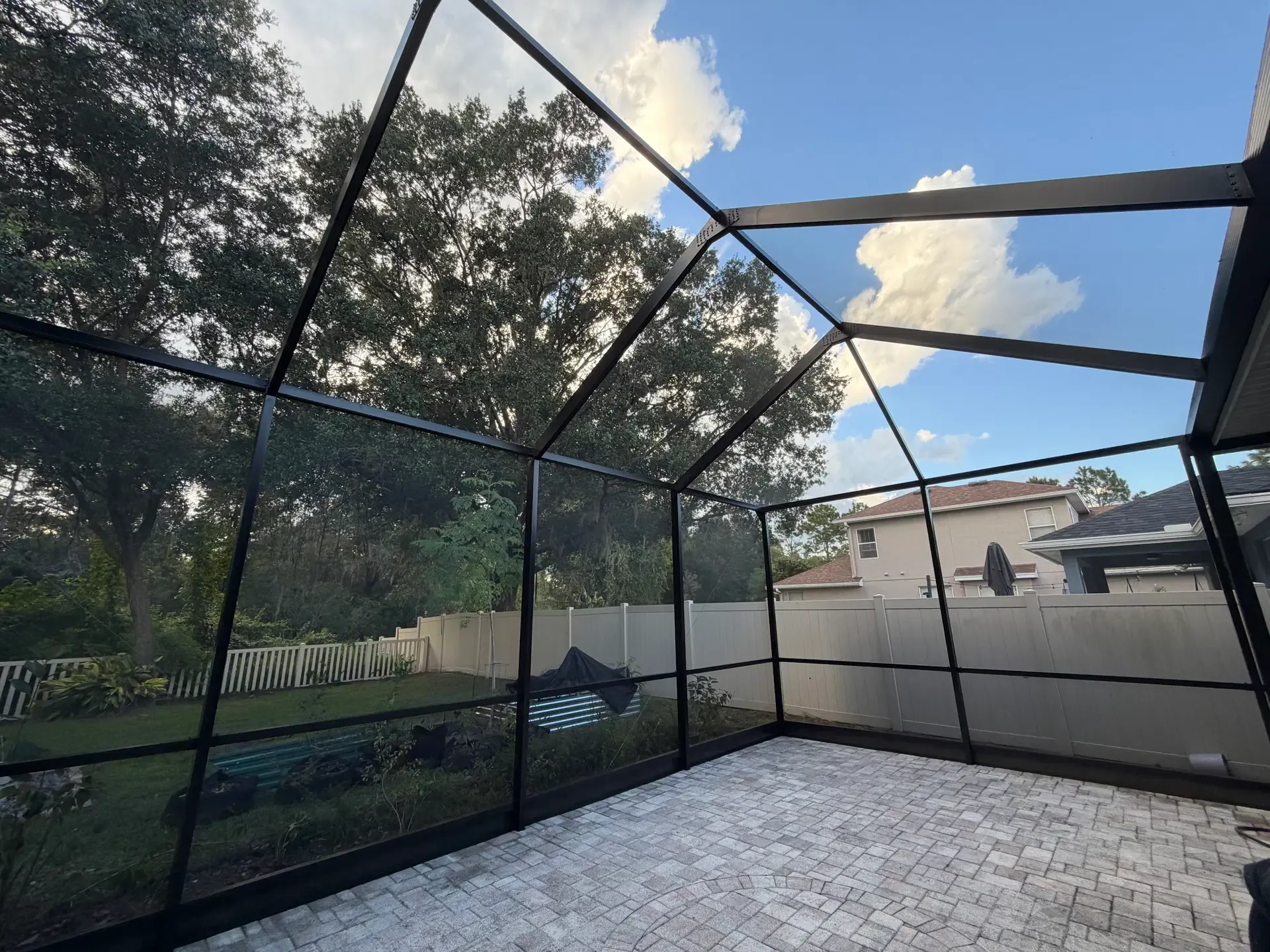 Freshly rescreened black-frame patio enclosure with clean sightlines over the backyard
